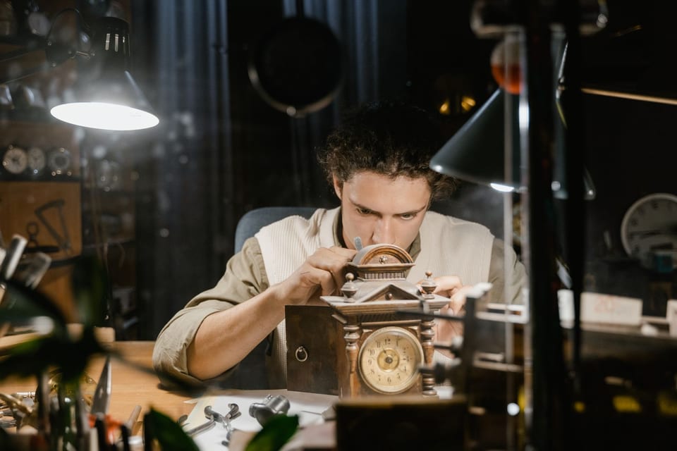 An ANKEROV master at the bench assembling a movement under a lamp